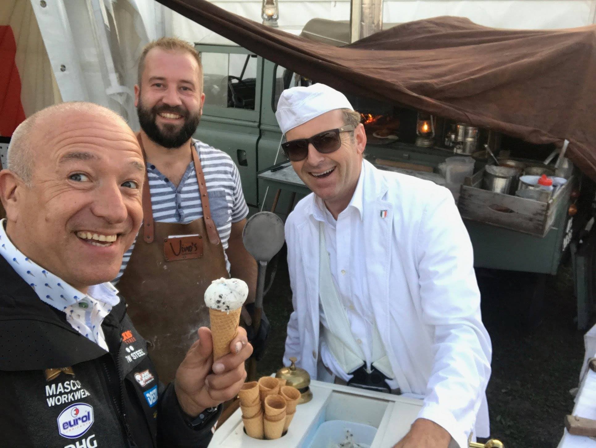 Zingende ijscoman maakt buiten bij een kraam een selfie met twee mannen met een hoorntje, zoals op een beurs