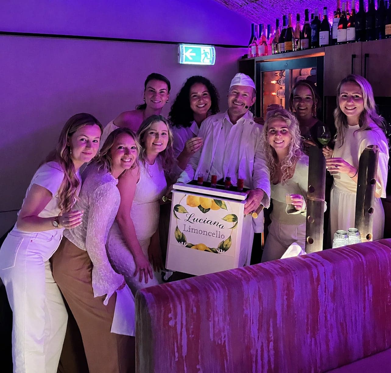 Gasten in het wit rond de limoncello-kist op een feest
