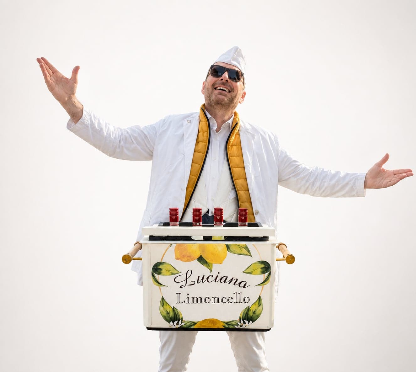 Luciano Limoncello in wit kostuum met armen wijd achter zijn handbeschilderde kist met citroenen