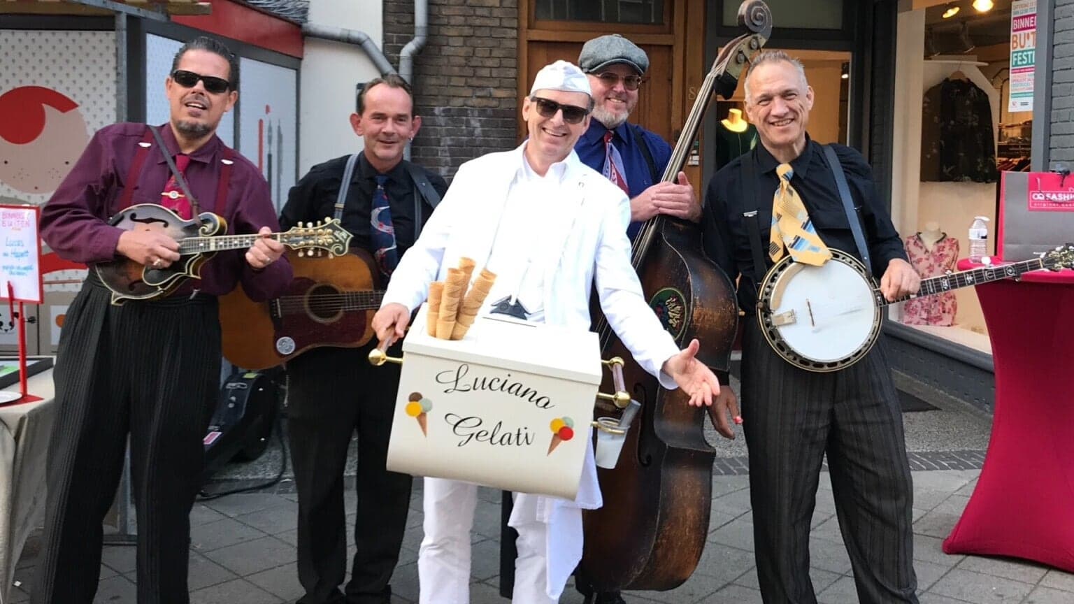 Luciano met zijn ijskist naast muzikanten met contrabas en banjo